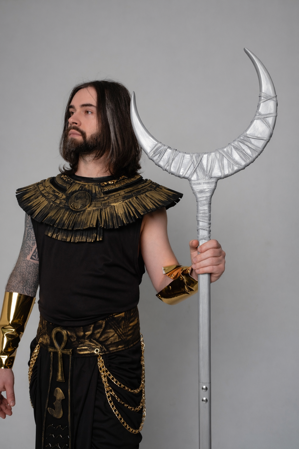 Person in elaborate costume holding a large silver weapon against a gray background