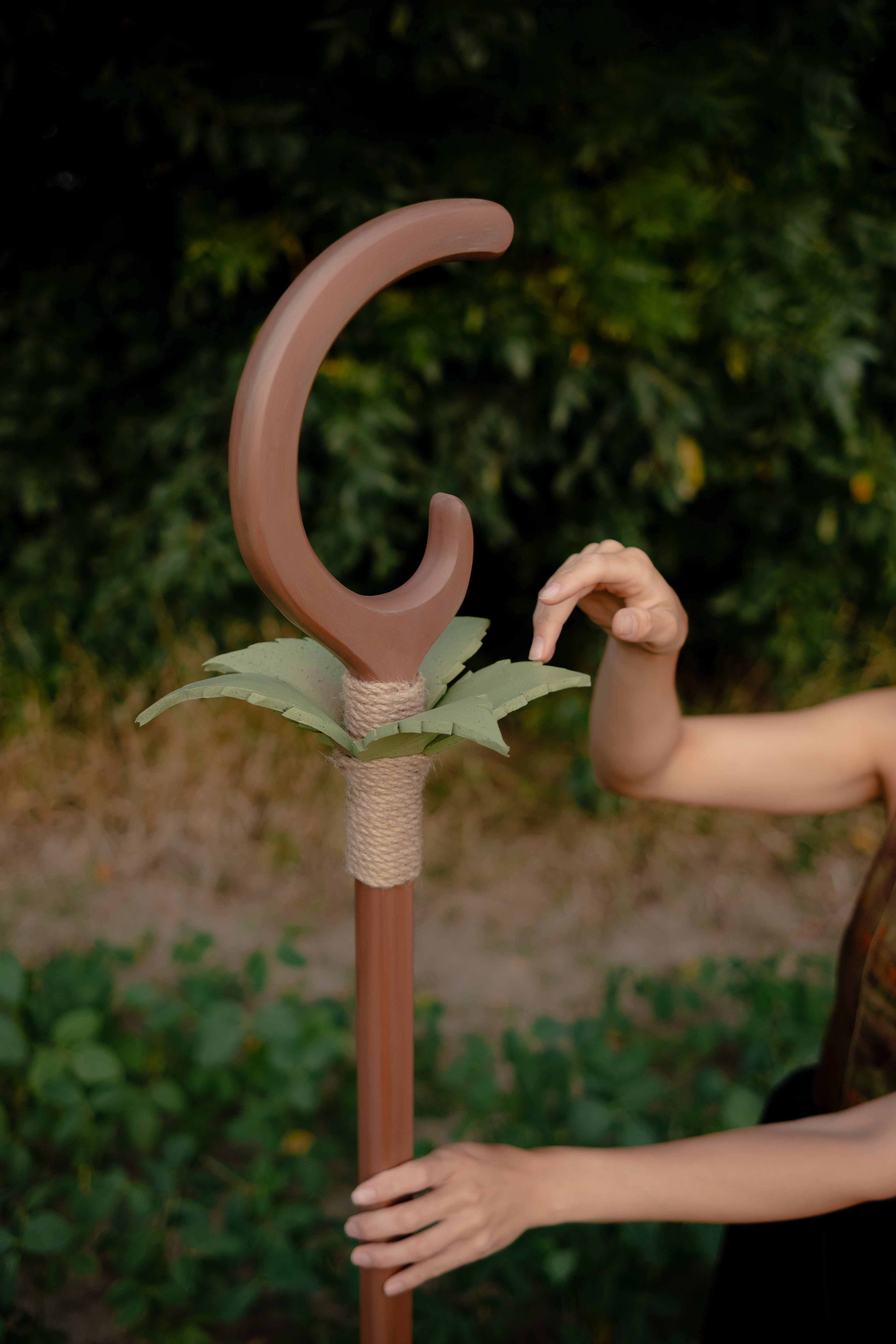 Close-up of hand holding wooden staff with crescent and leaf decoration