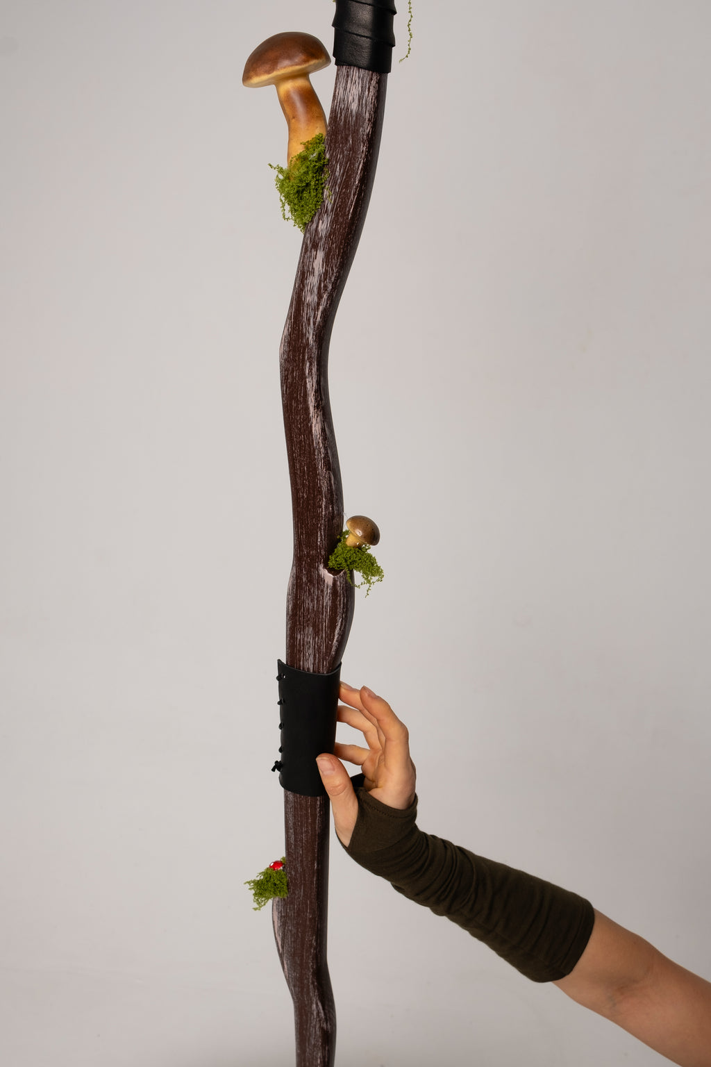 Wooden staff with a hand holding it against a plain background