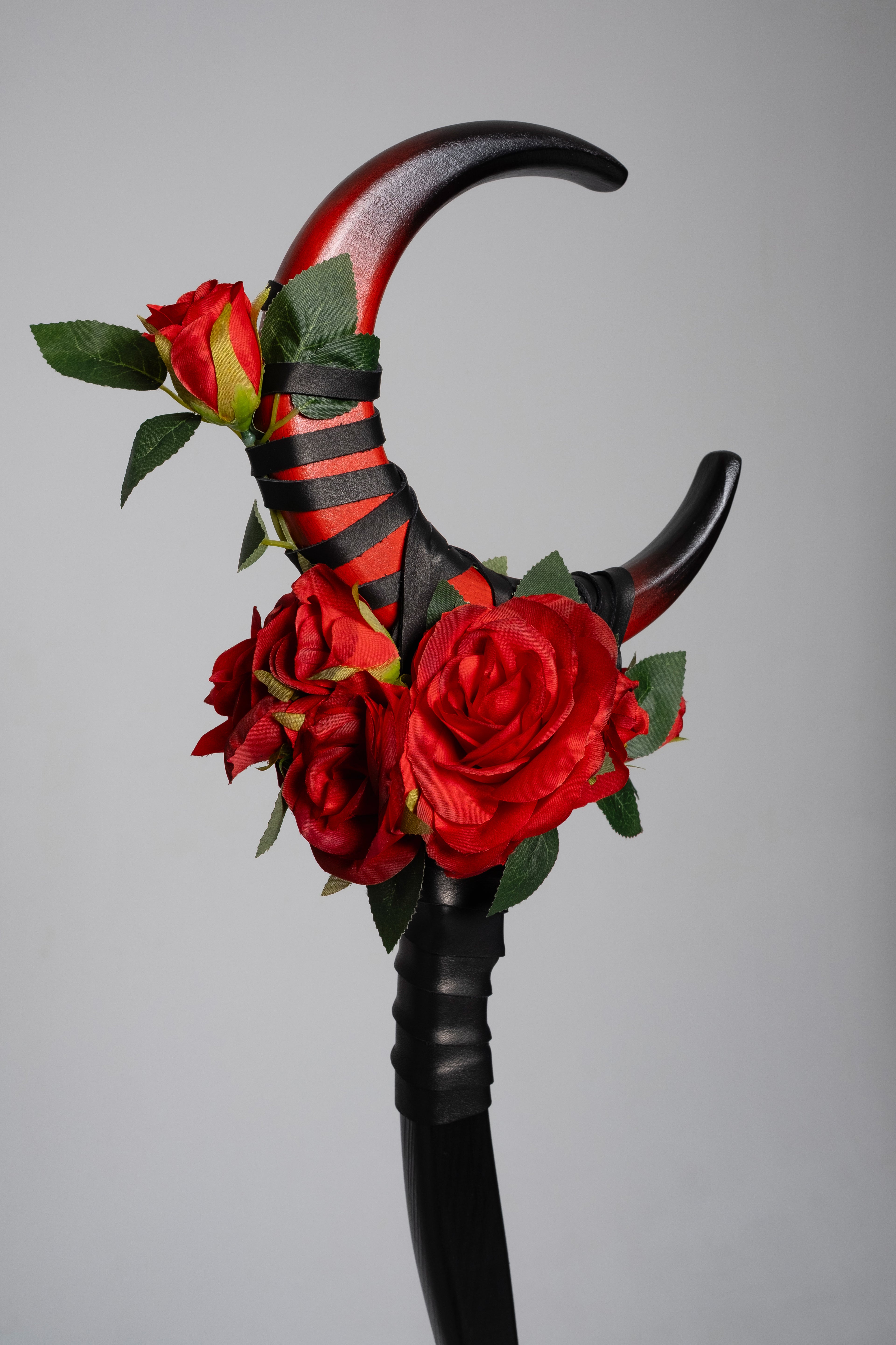 Decorative staff with red roses and black and red striped accents on a gray background