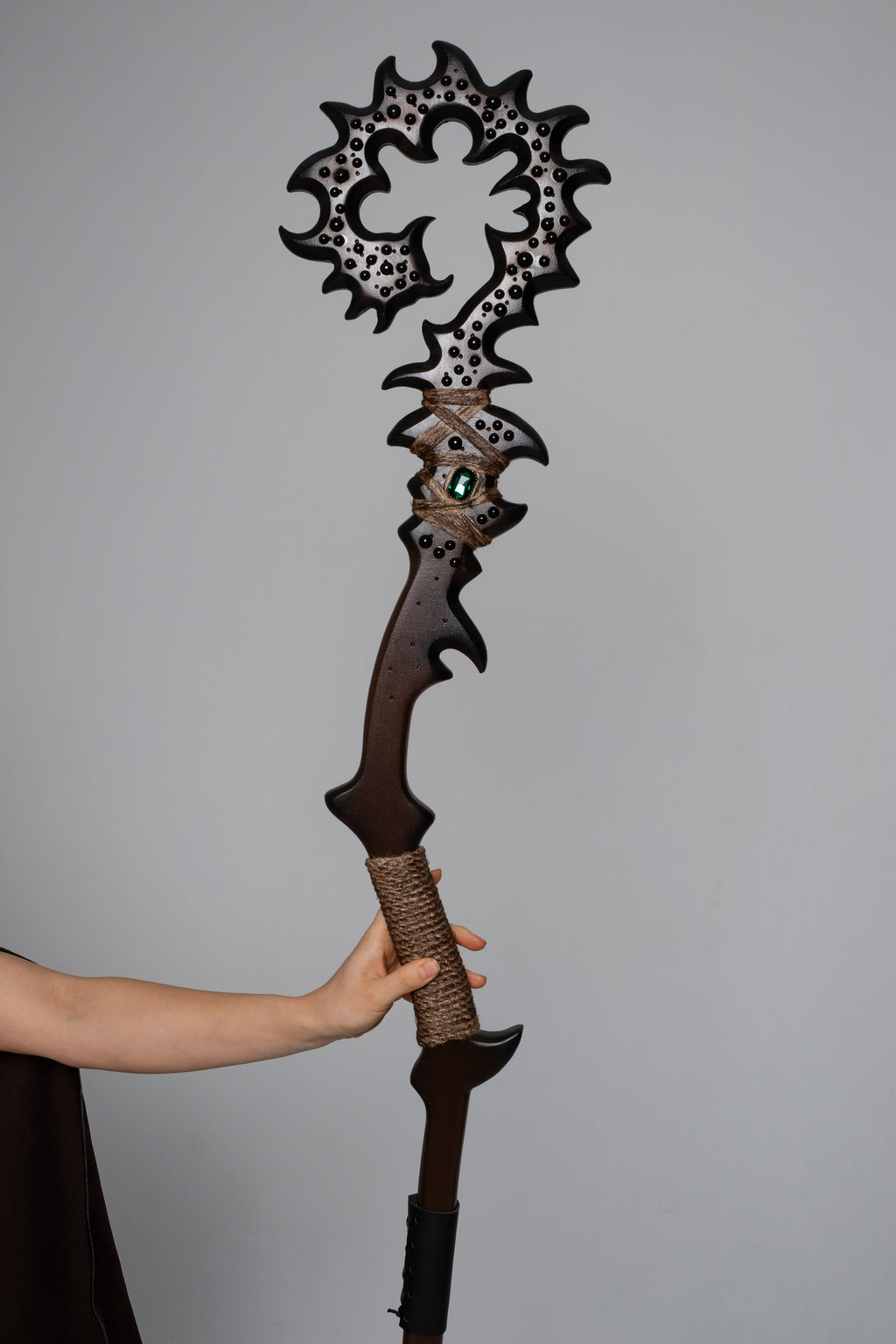 Model holding dark woodland fantasy staff with brown costume styling