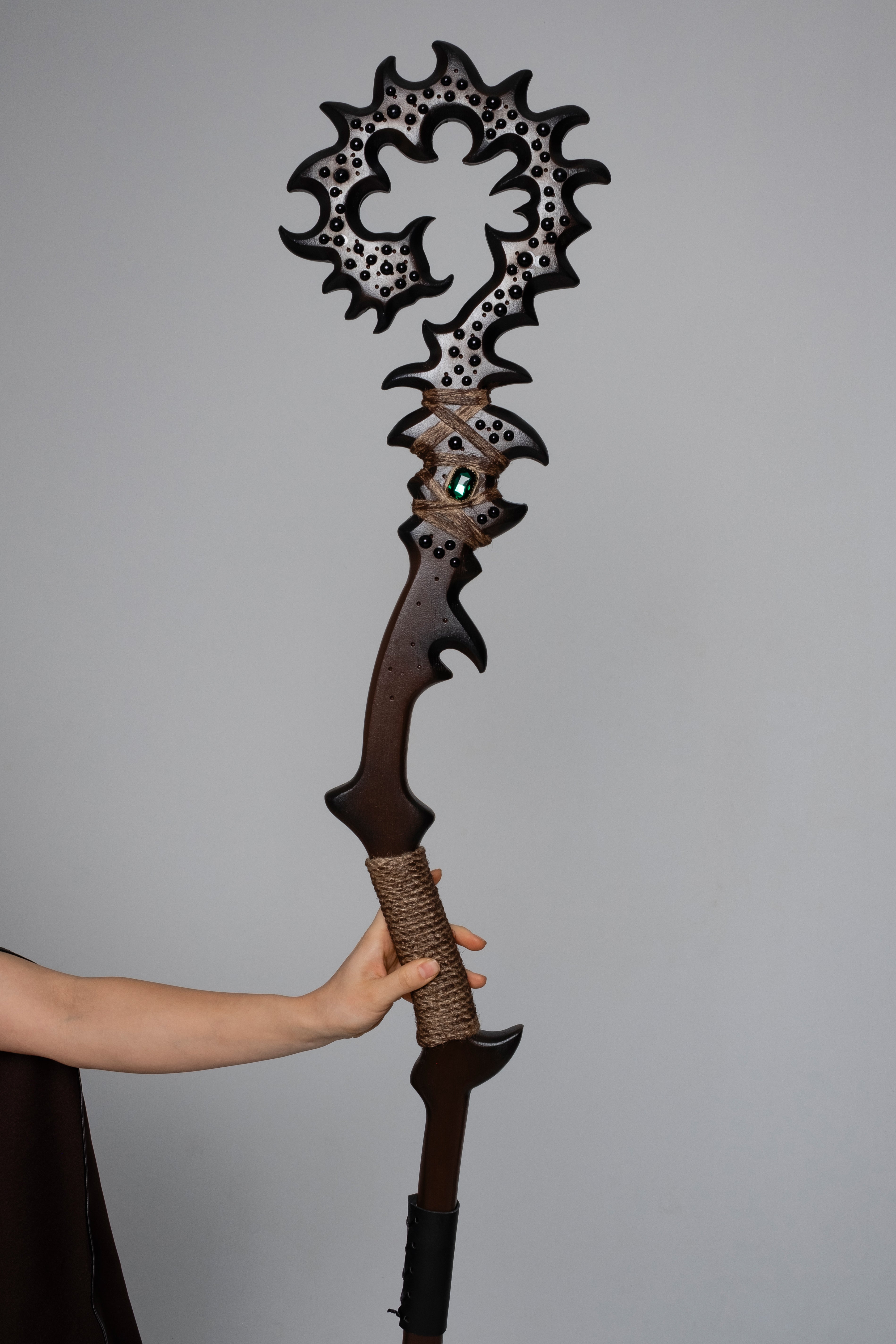 Model holding dark woodland fantasy staff with brown costume styling