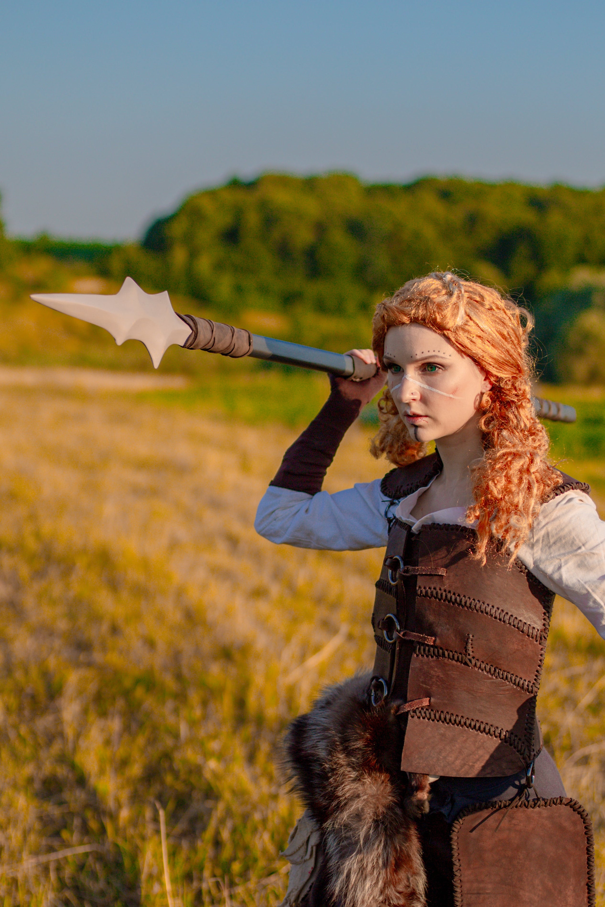 Person in medieval warrior costume holding a spear in a field
