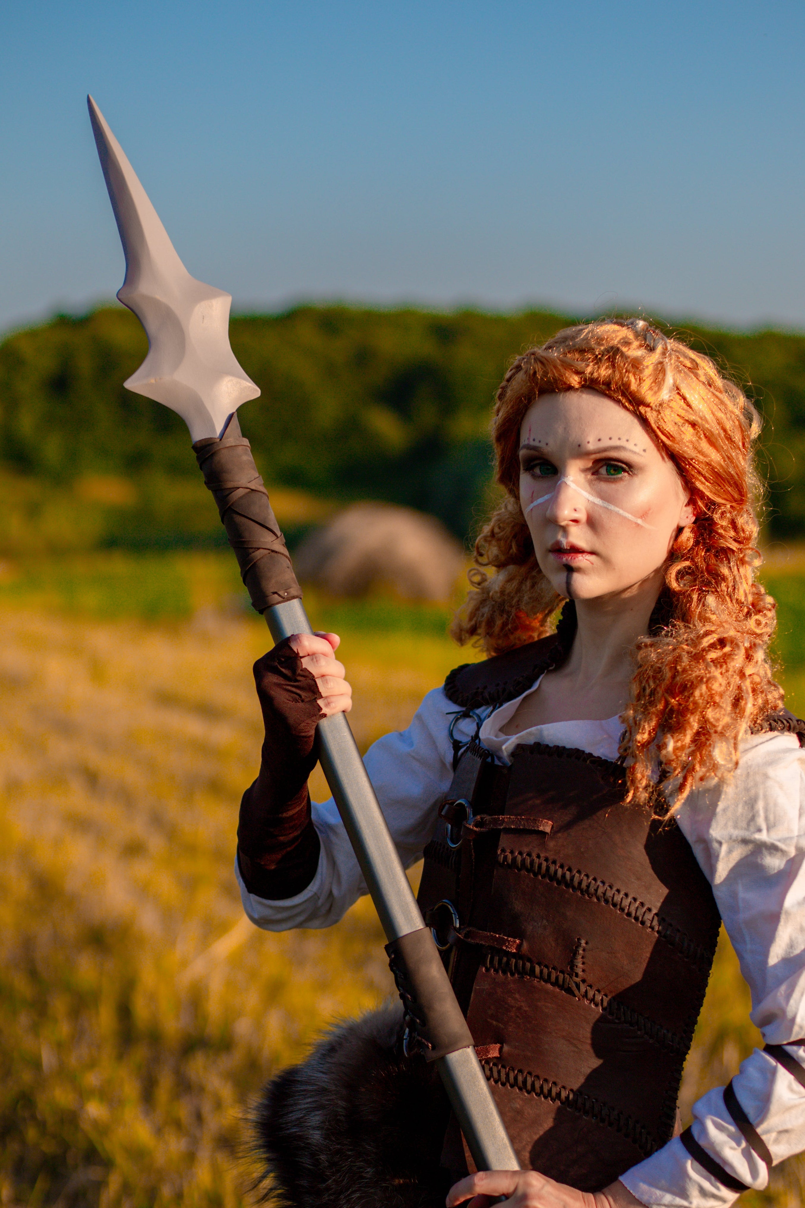 Person in a fantasy costume holding a spear in a field