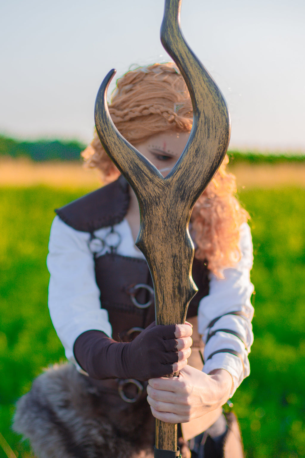 Model holding curved wooden Staff of Luminae with brown fantasy costume styling