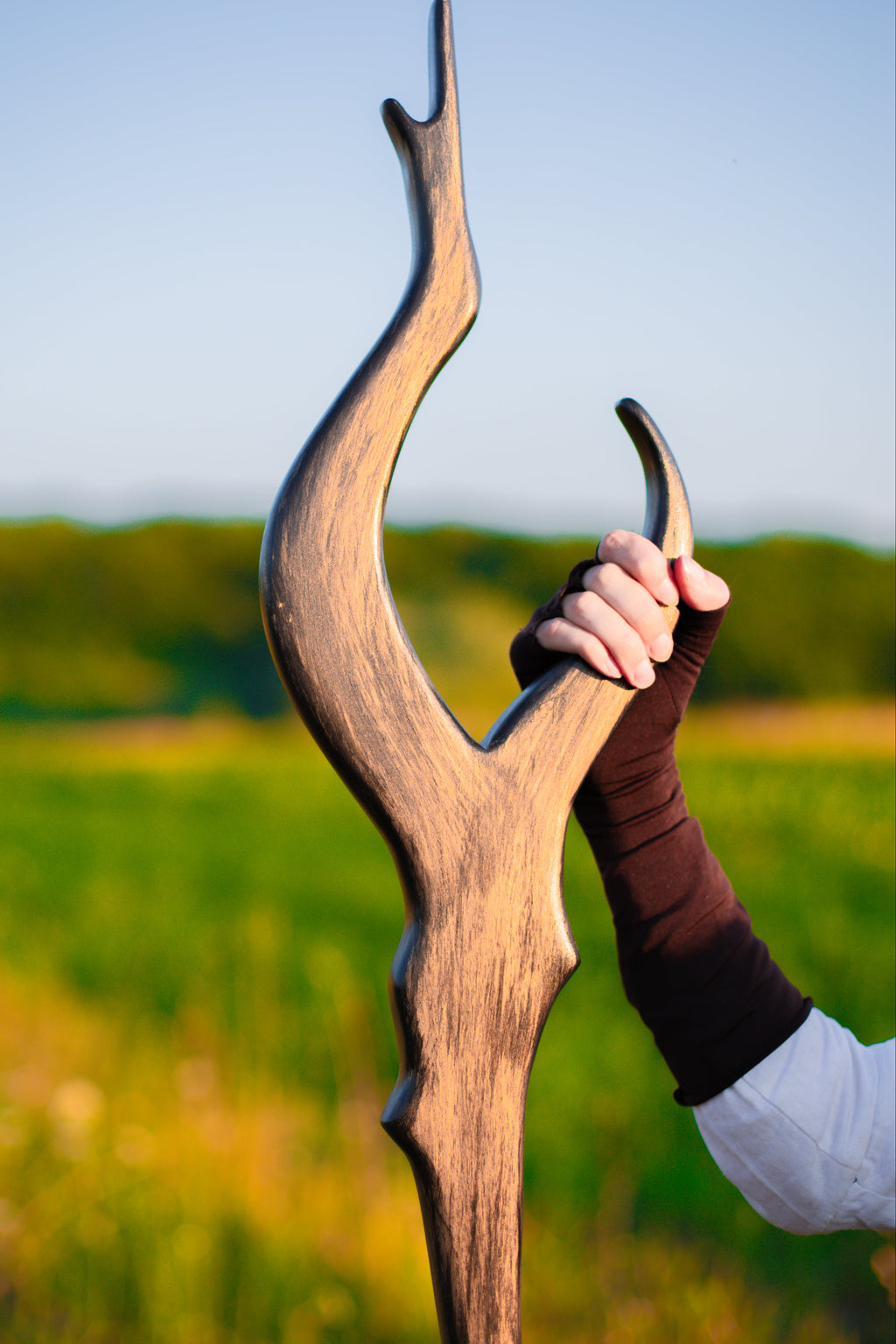 Staff of Luminae handmade wooden fantasy staff held outdoors in a green field