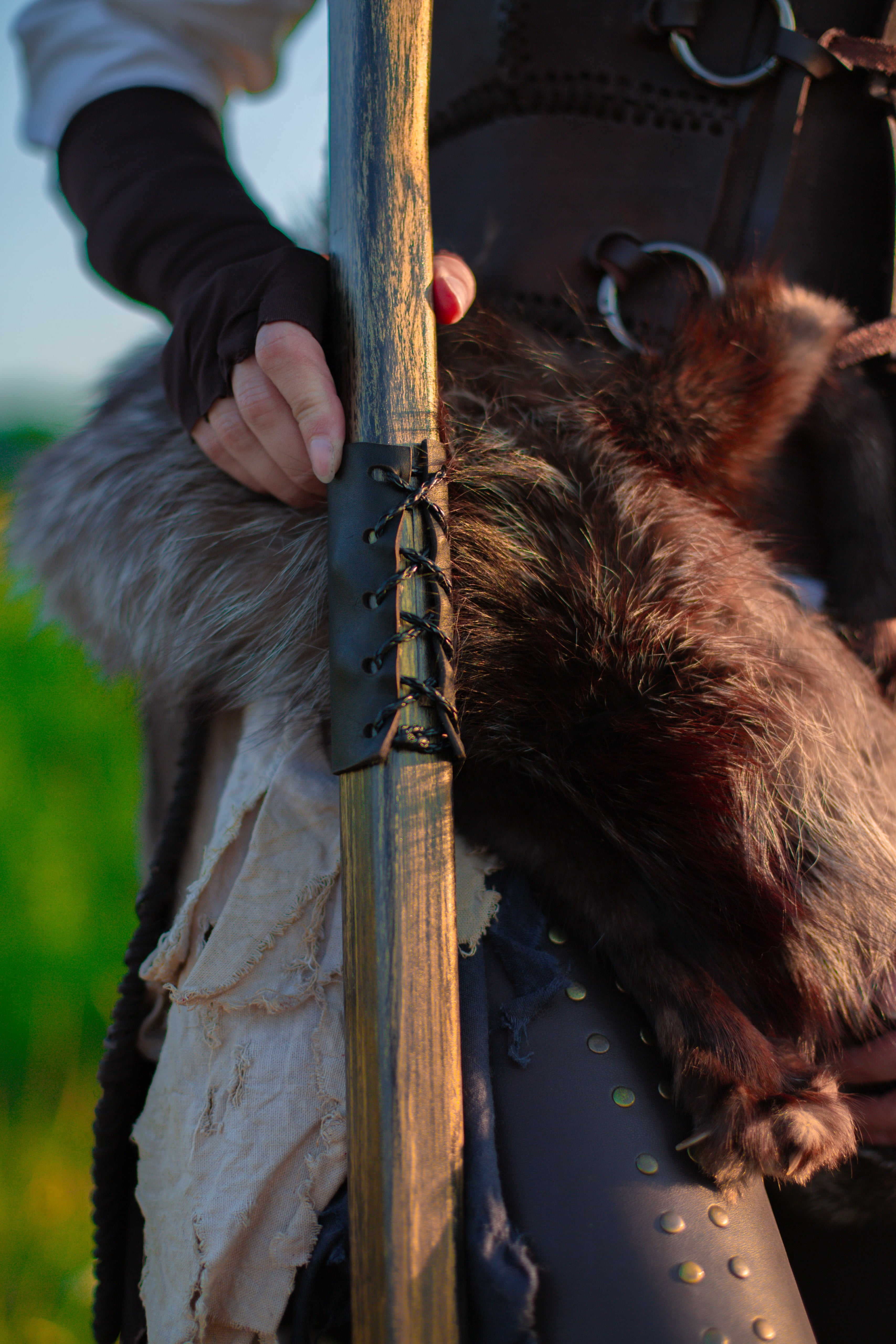 Close-up of hand holding varnished wooden fantasy staff with carved curved design