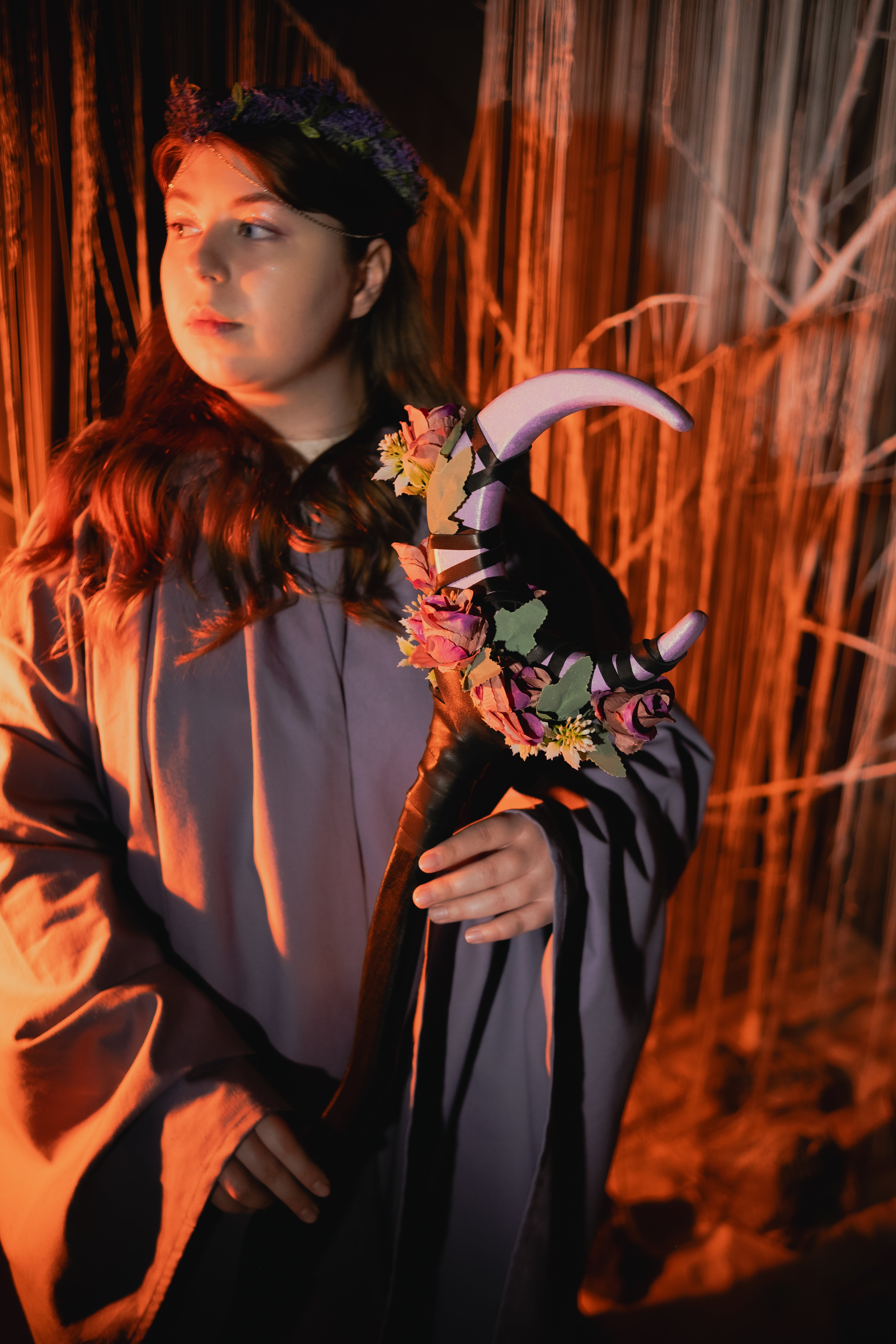 Person in a costume with floral accessories and horns against a dark background
