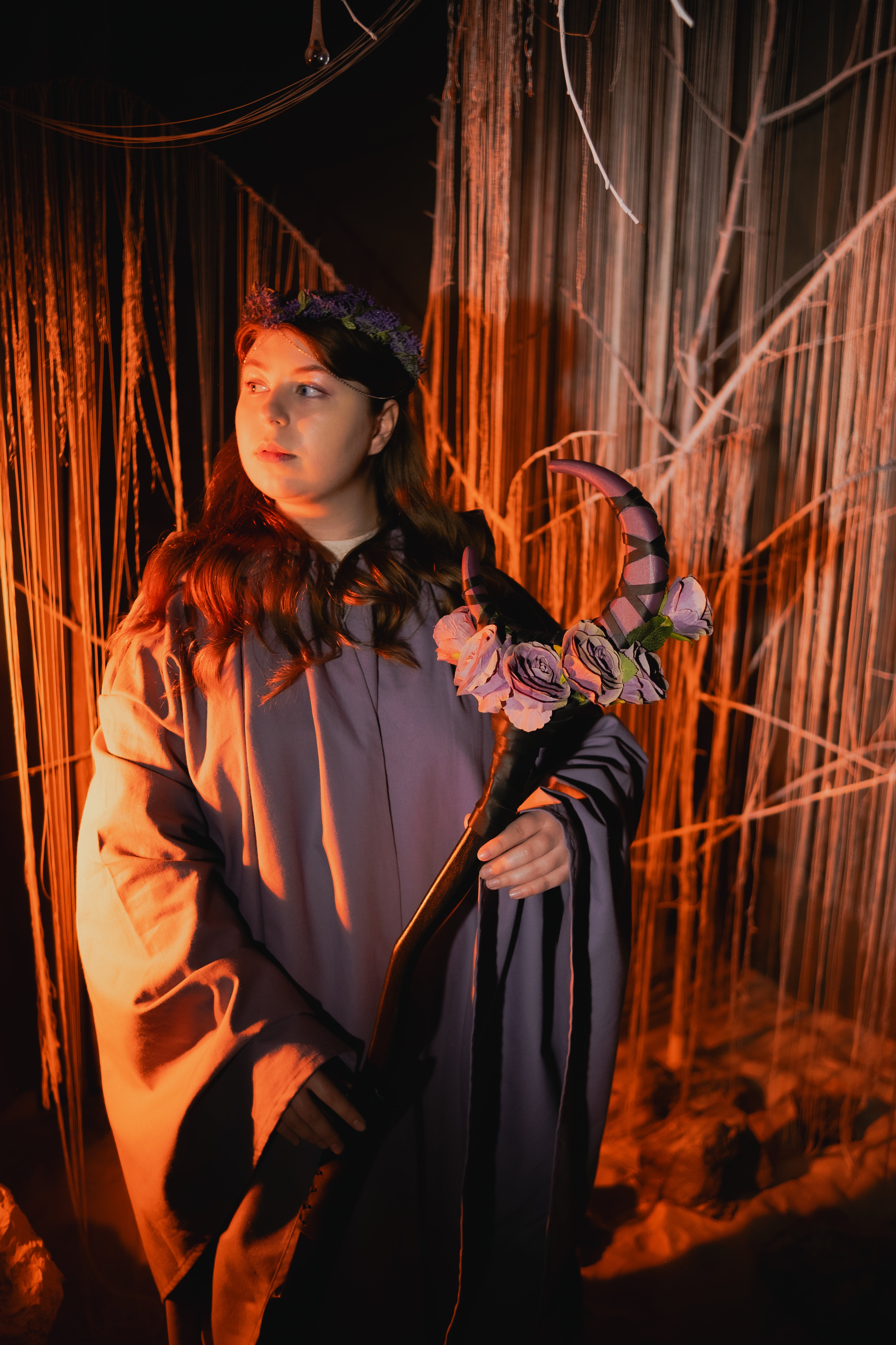 Person holding a bouquet of flowers in a dimly lit setting with string lights.