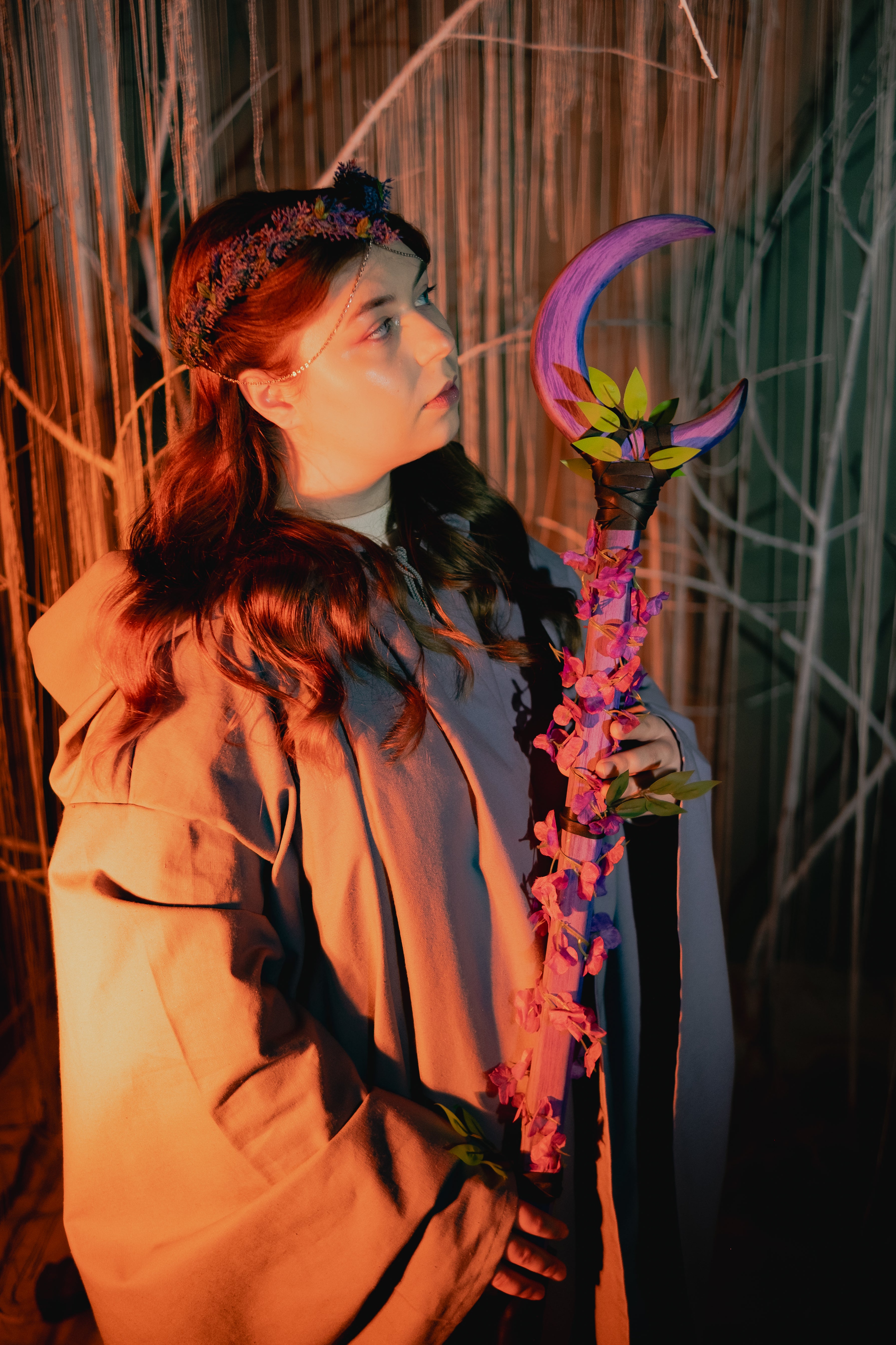 Person holding a colorful staff with a crescent moon design against a textured wall.