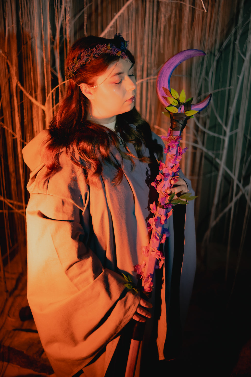 Person holding a colorful staff with floral decorations against a natural background